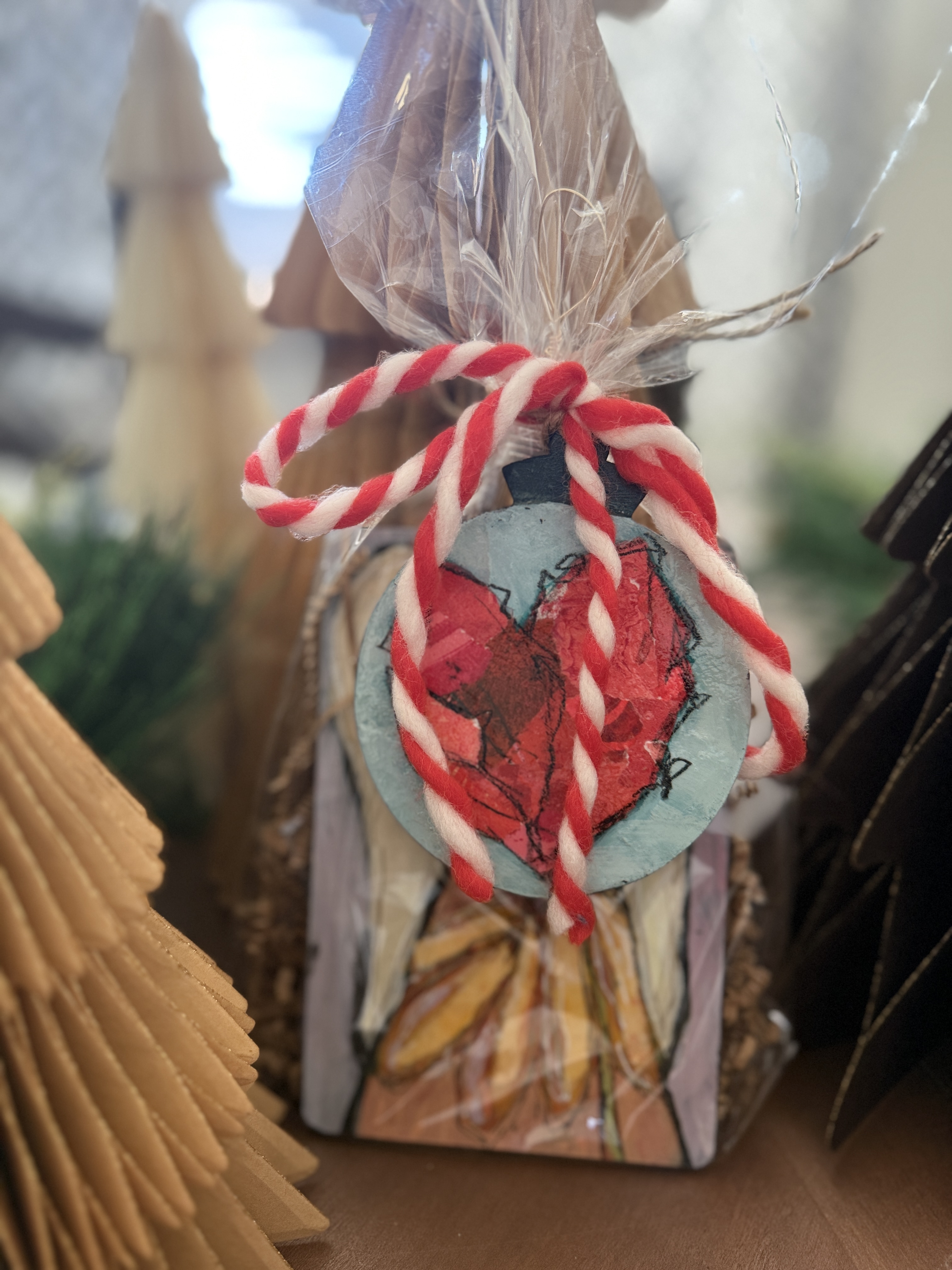 Handwrapped ornament sitting on table with holiday decorations